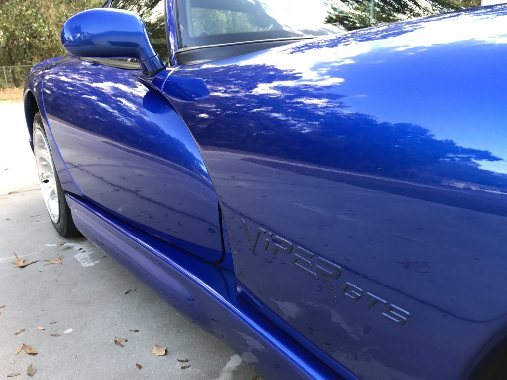 A blue dodge viper is parked on the side of the road