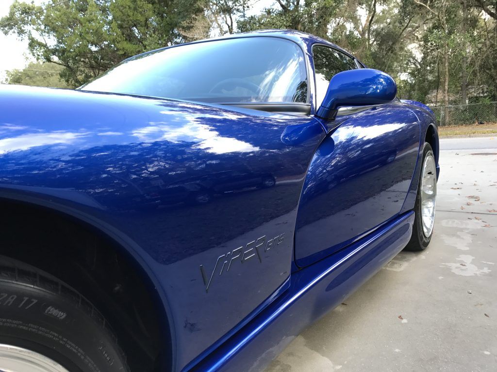A blue dodge viper is parked on the side of the road