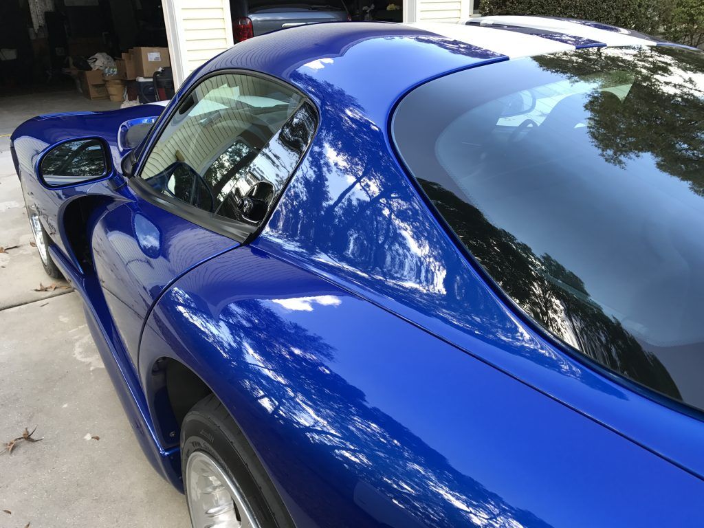 A blue sports car is parked in a driveway in front of a garage.