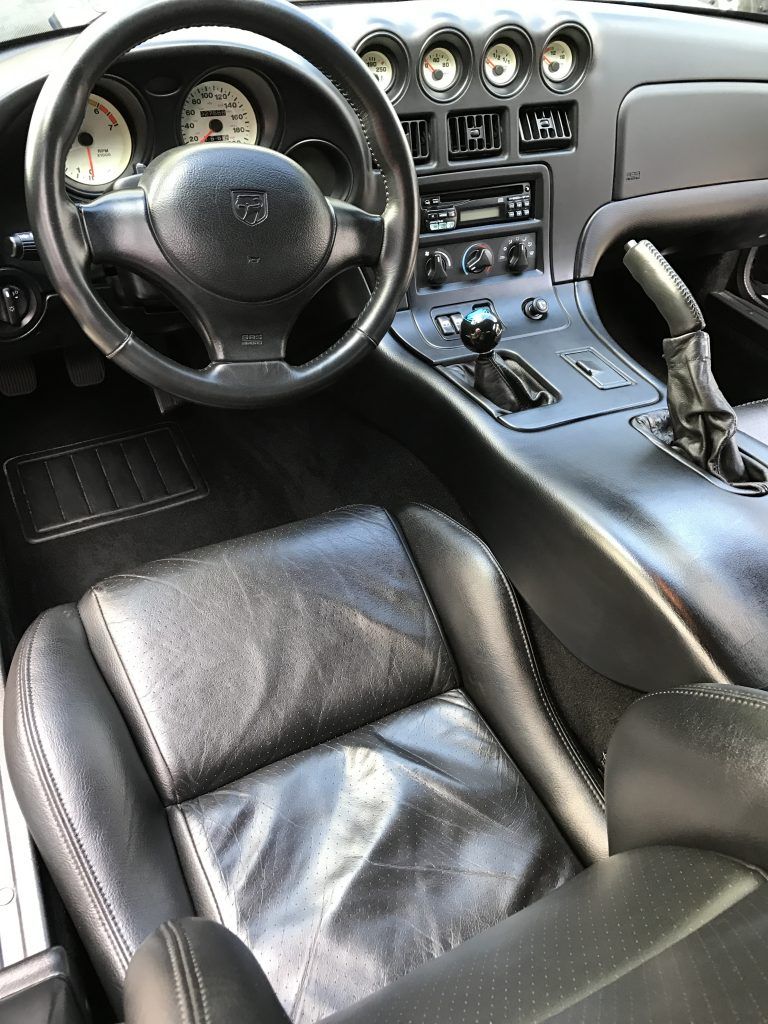 The interior of a dodge viper with black leather seats and a steering wheel.