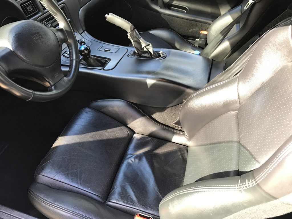 The interior of a car with black leather seats and a steering wheel.