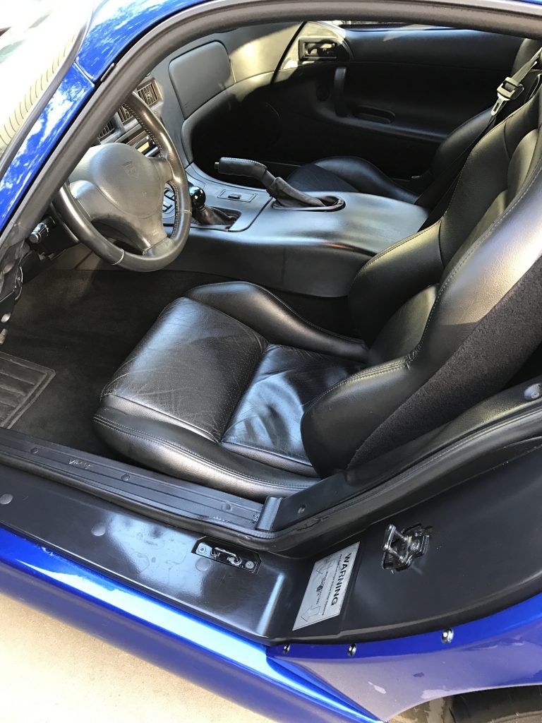 The interior of a blue sports car with the door open.