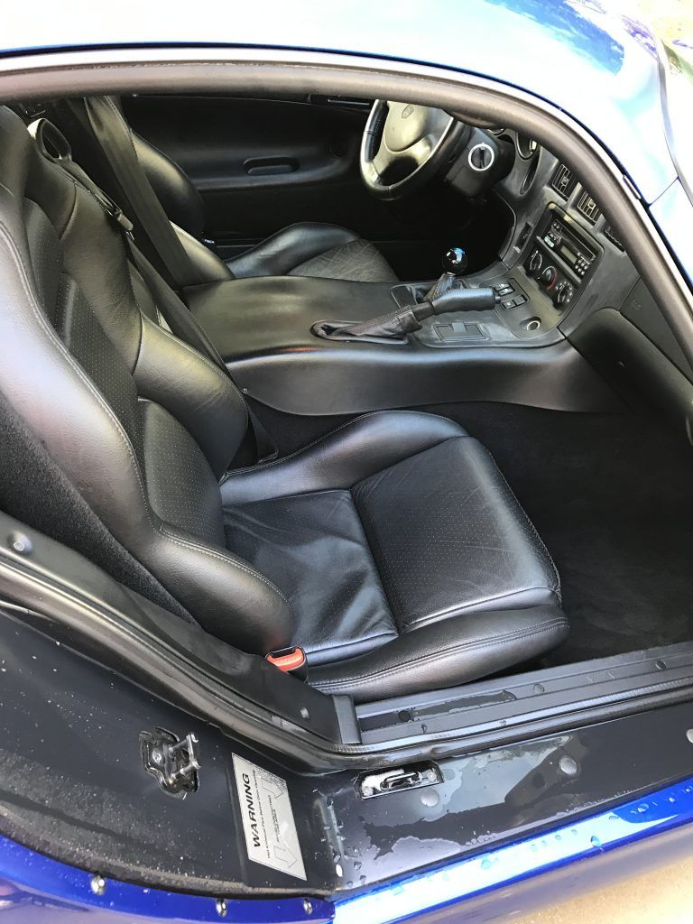 The interior of a blue sports car with the door open.