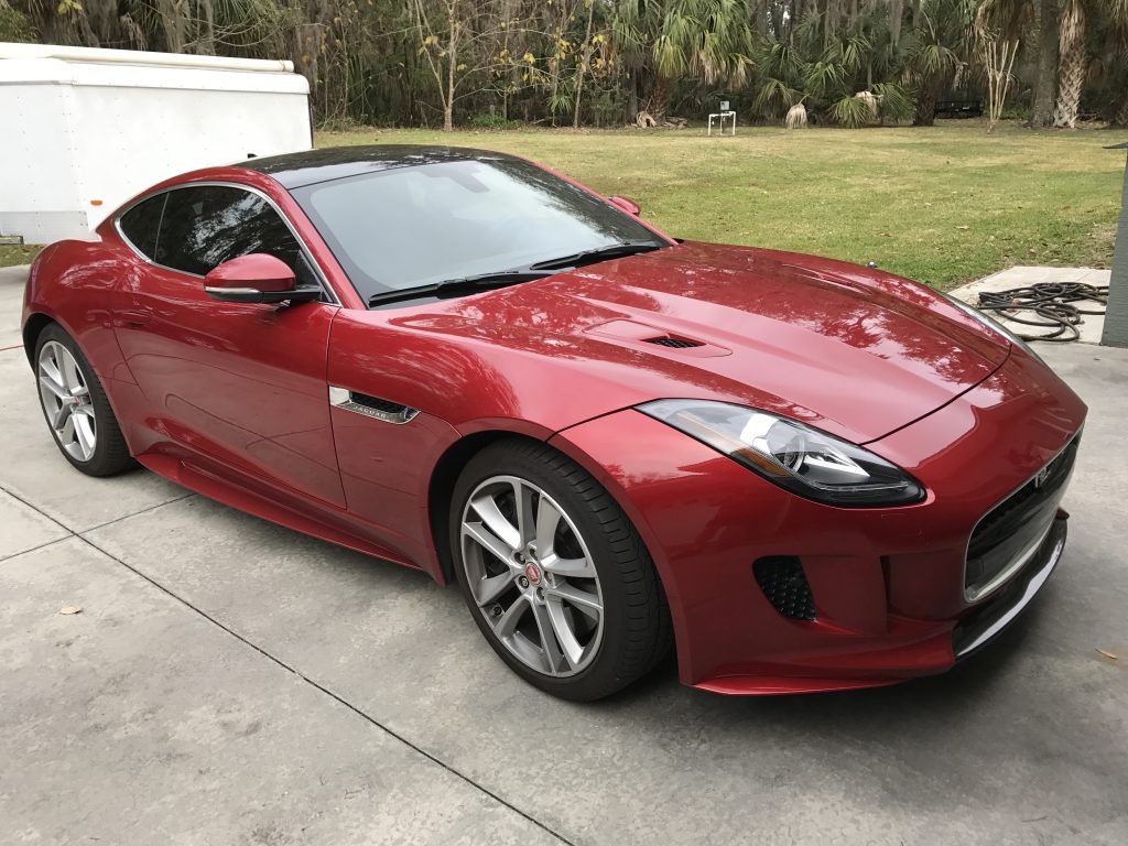 A red jaguar f type is parked in a driveway.