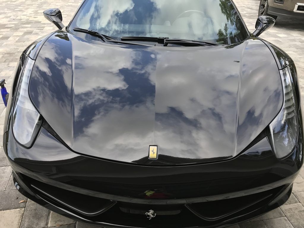 A black ferrari 458 italia is parked in a driveway.
