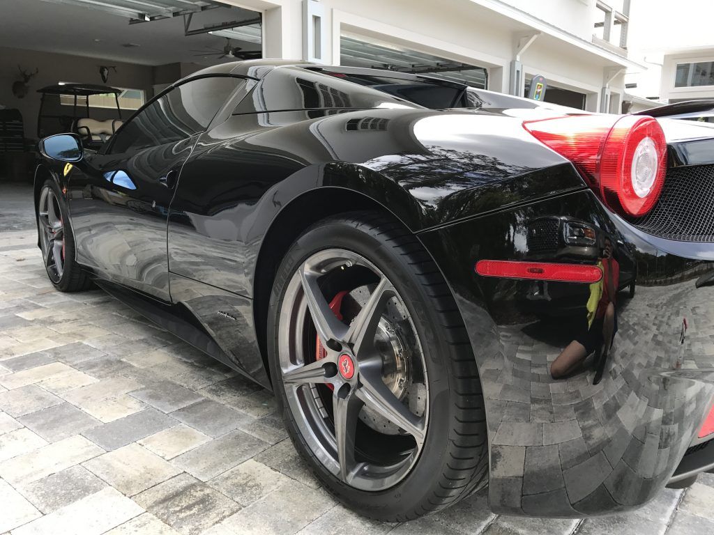 A black sports car is parked in front of a garage.