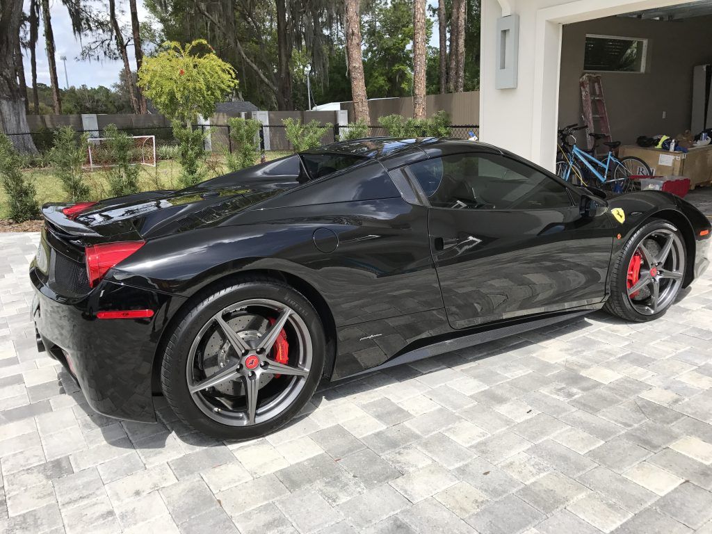 A black ferrari sports car is parked in a garage.