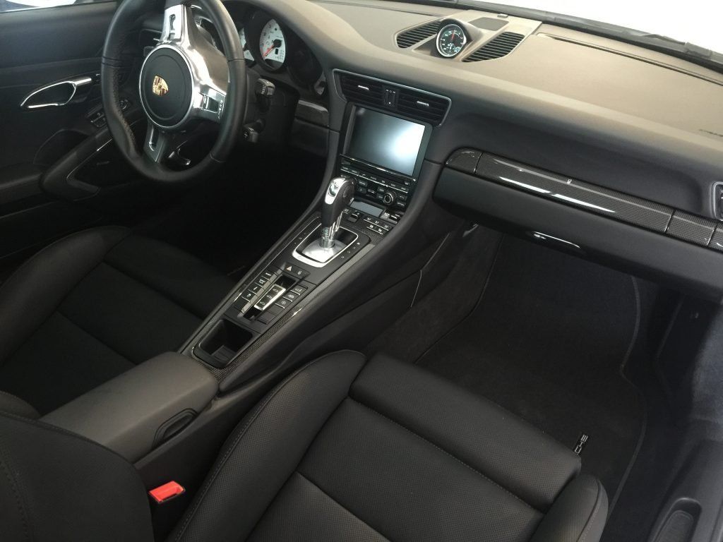 The interior of a porsche 911 with black seats and a steering wheel