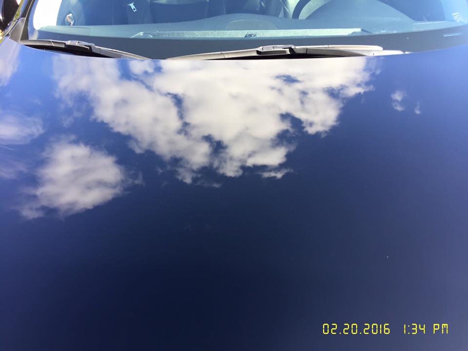 A close up of a car windshield with clouds reflected in it