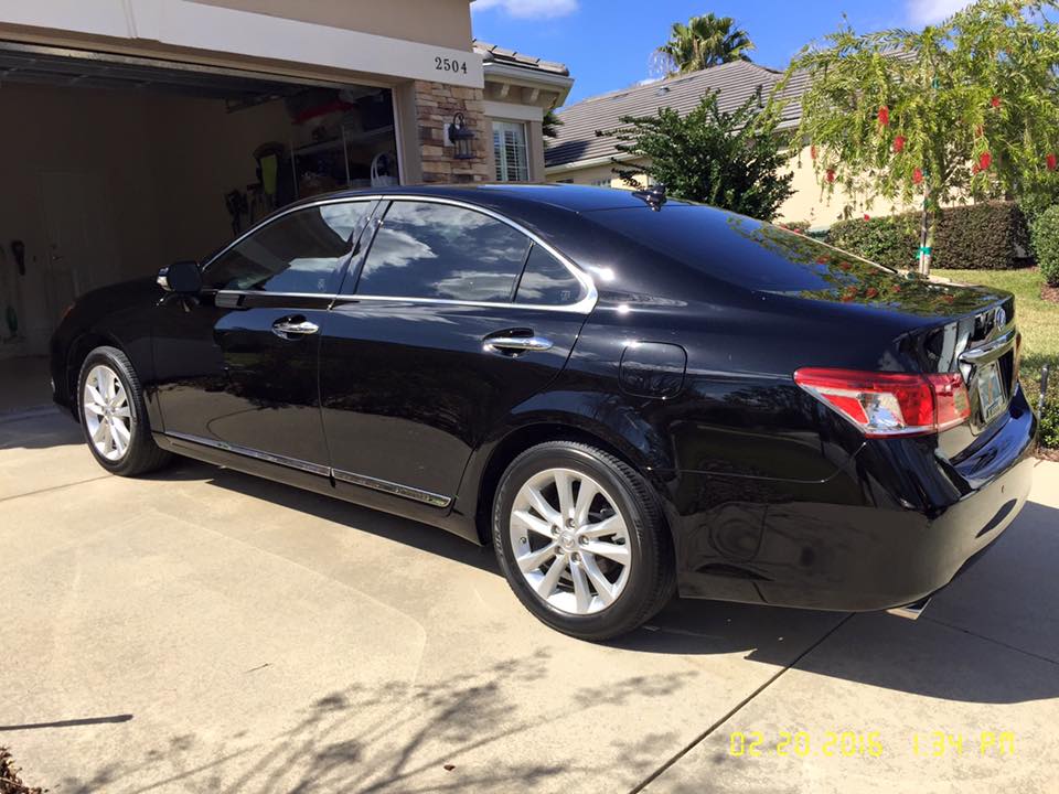 A black car is parked in a driveway in front of a garage.