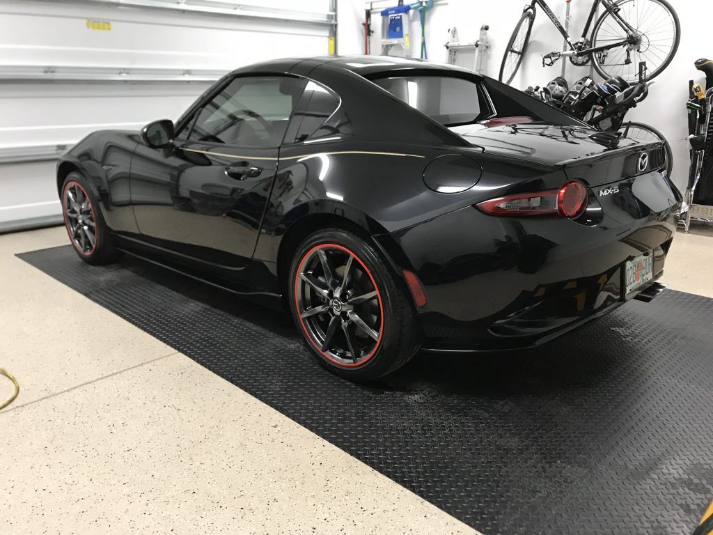 A black sports car is parked in a garage next to a bicycle rack.