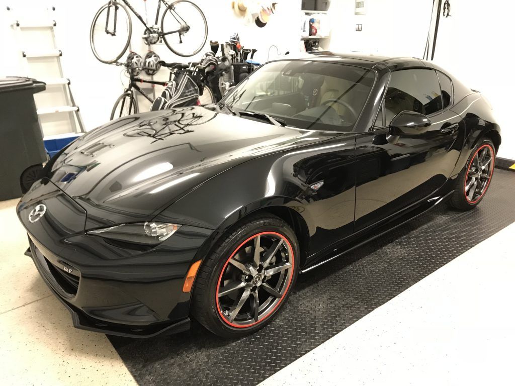 A black sports car is parked in a garage.