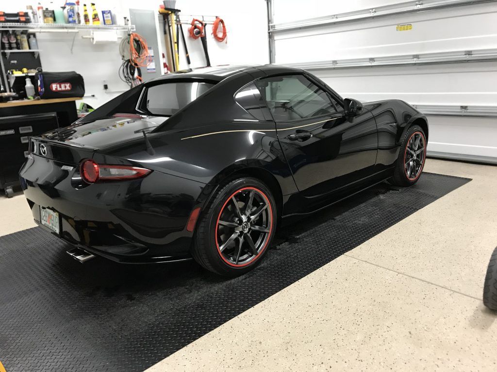 A black sports car is parked in a garage.