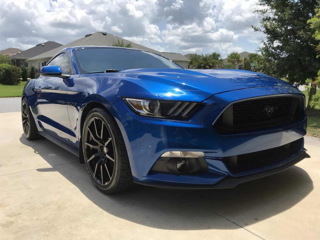 A blue ford mustang is parked in a driveway.