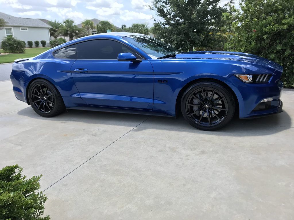 A blue ford mustang is parked in a driveway.