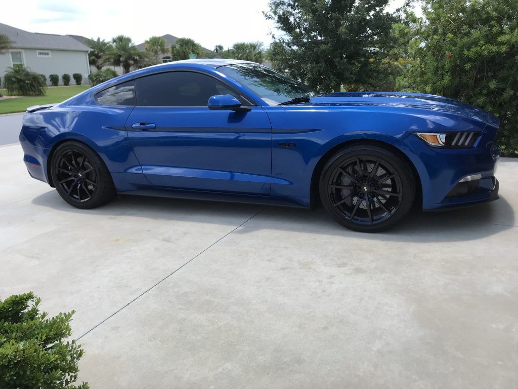 A blue ford mustang is parked in a driveway.