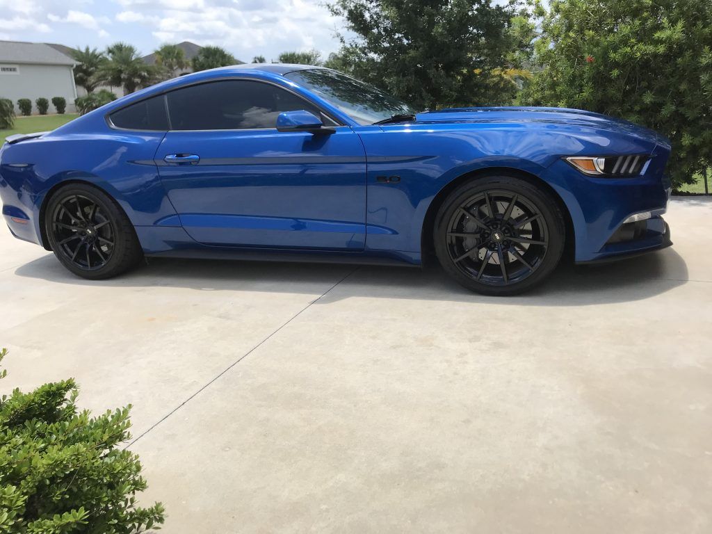 A blue ford mustang is parked in a driveway.