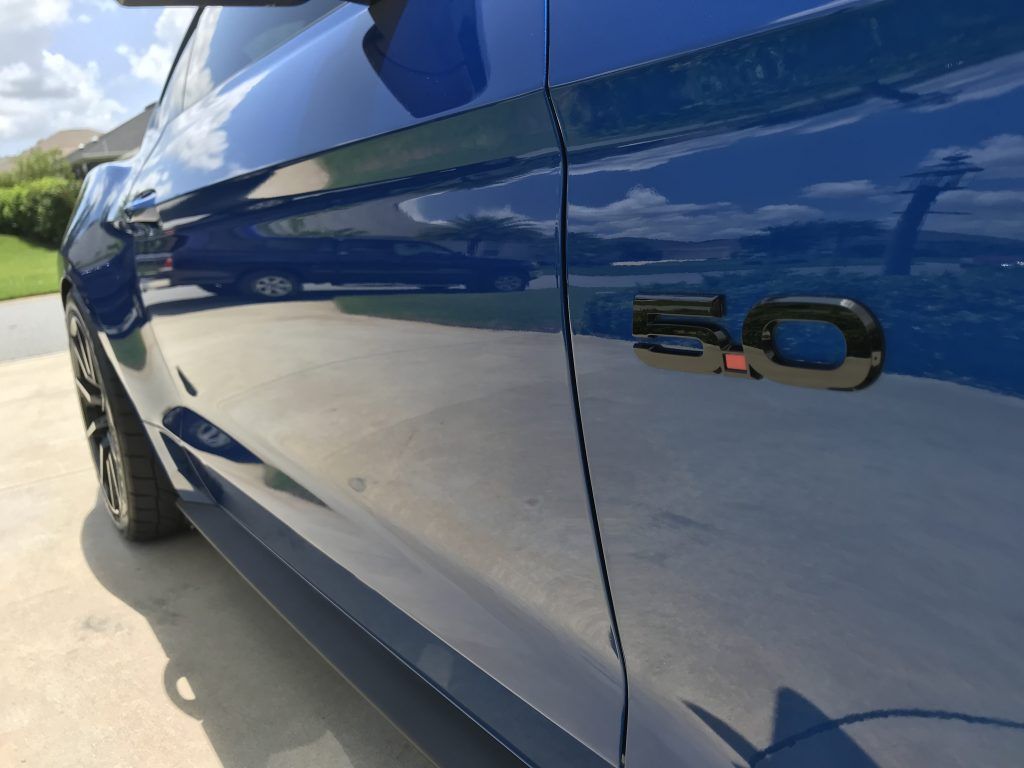 A blue ford mustang is parked in a driveway