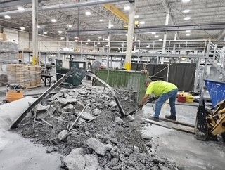 A man is digging in a pile of rocks in a warehouse.