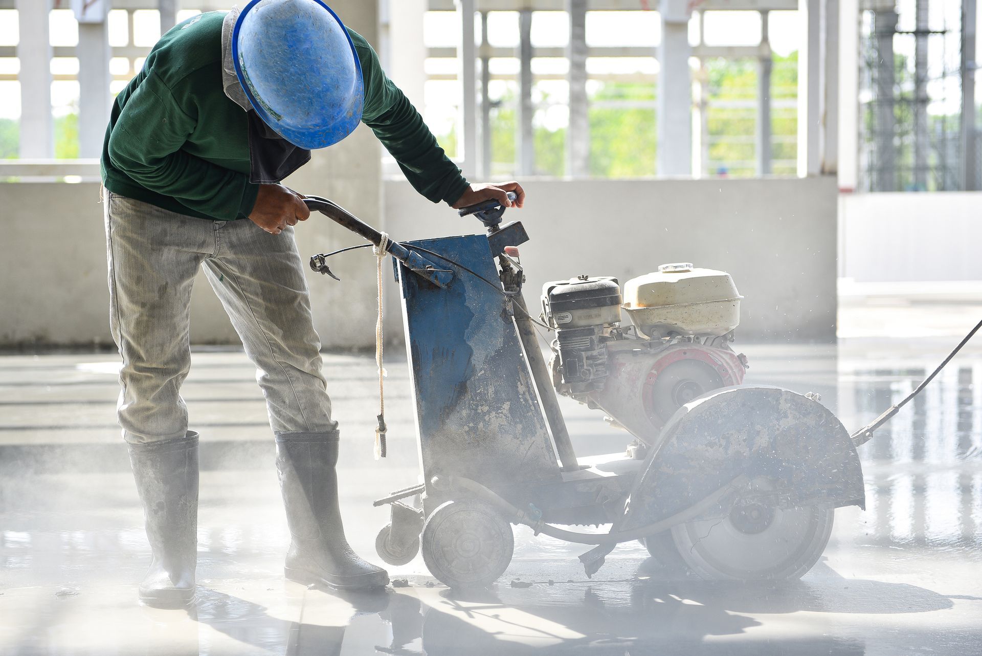 Concrete drilling service contractor using a cutting machine in a construction factory building.