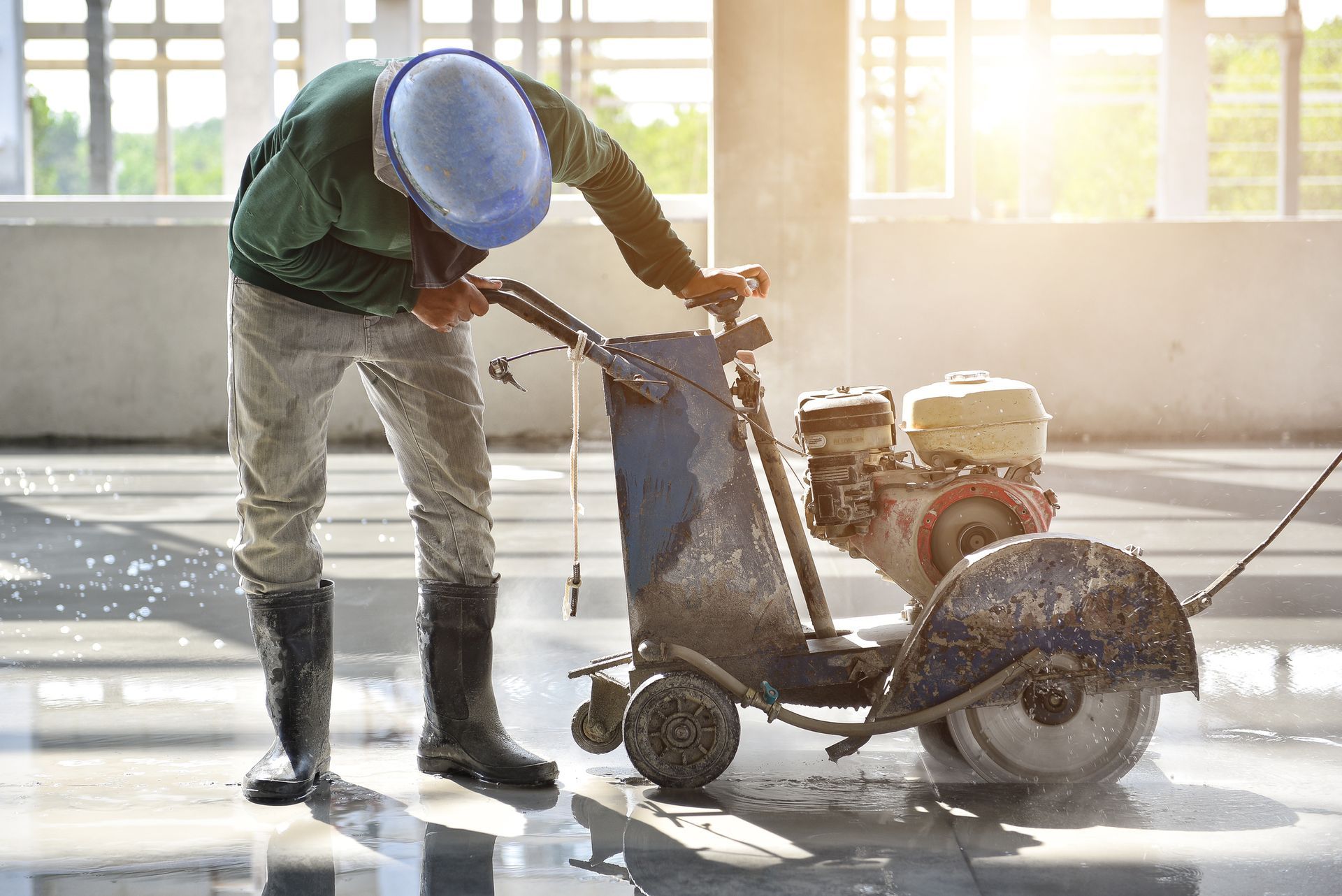 Worker performing commercial concrete cutting with machine to create expansion and isolation joints.