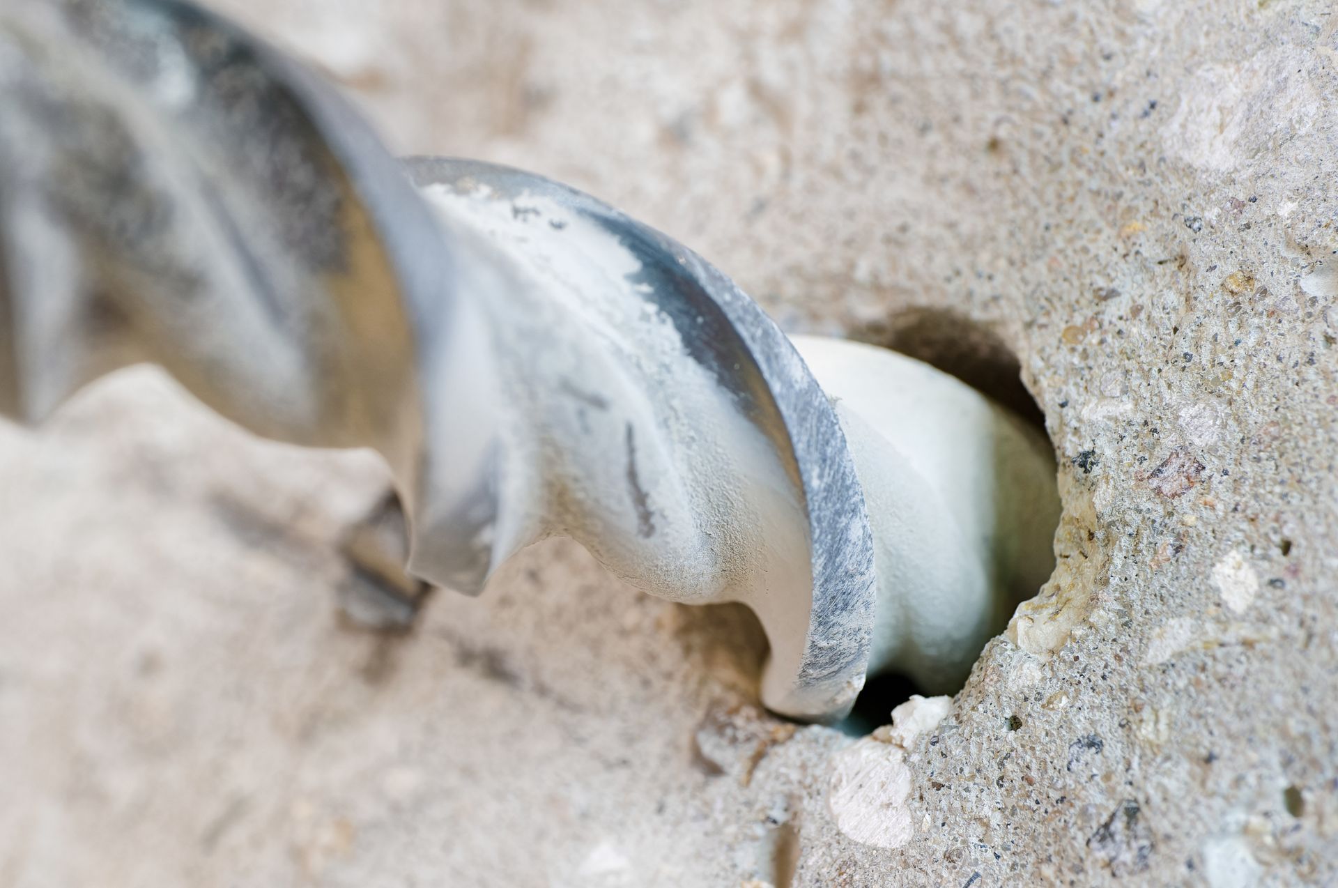 Stone drilling bit and concrete wall, close-up shot, industrial background.