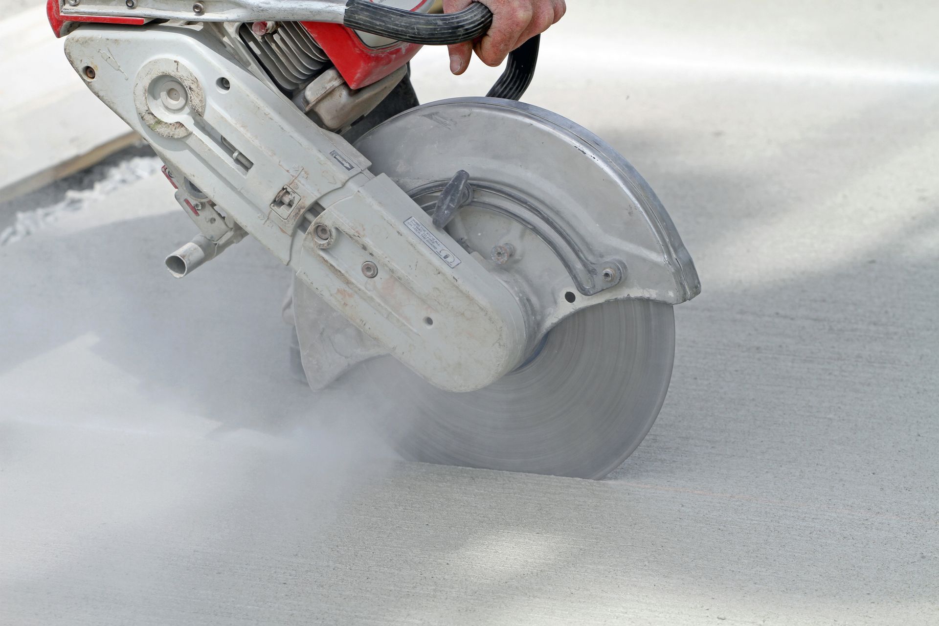 Worker using saw for commercial concrete cutting on construction site.