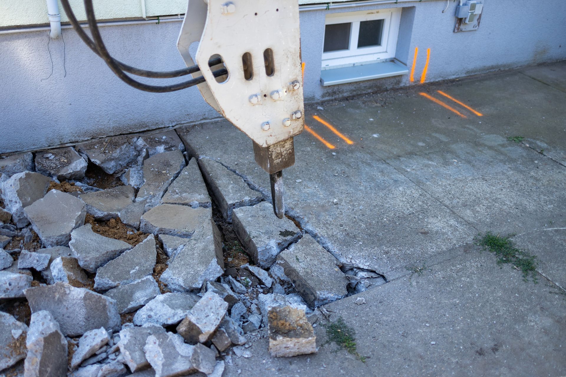 A hydraulic breaker attached to an excavator demolishes concrete pavement. A hydraulic breaker attached to an excavator demolishes concrete pavement.