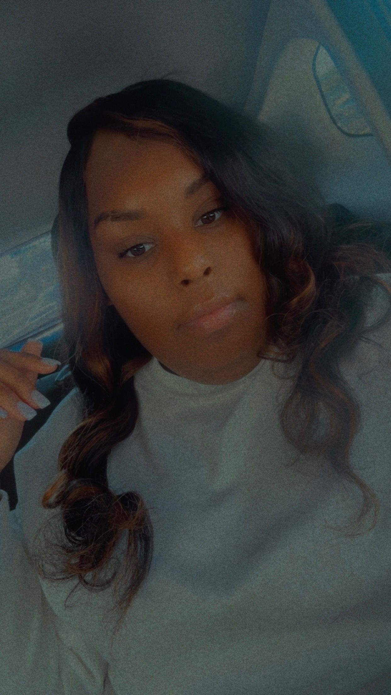 Woman with wavy dark hair, wearing a gray sweatshirt, looking at the camera.