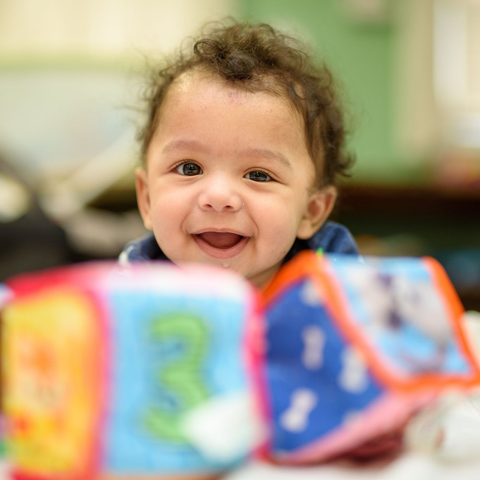 A baby is laying on a blanket in a bouncer.