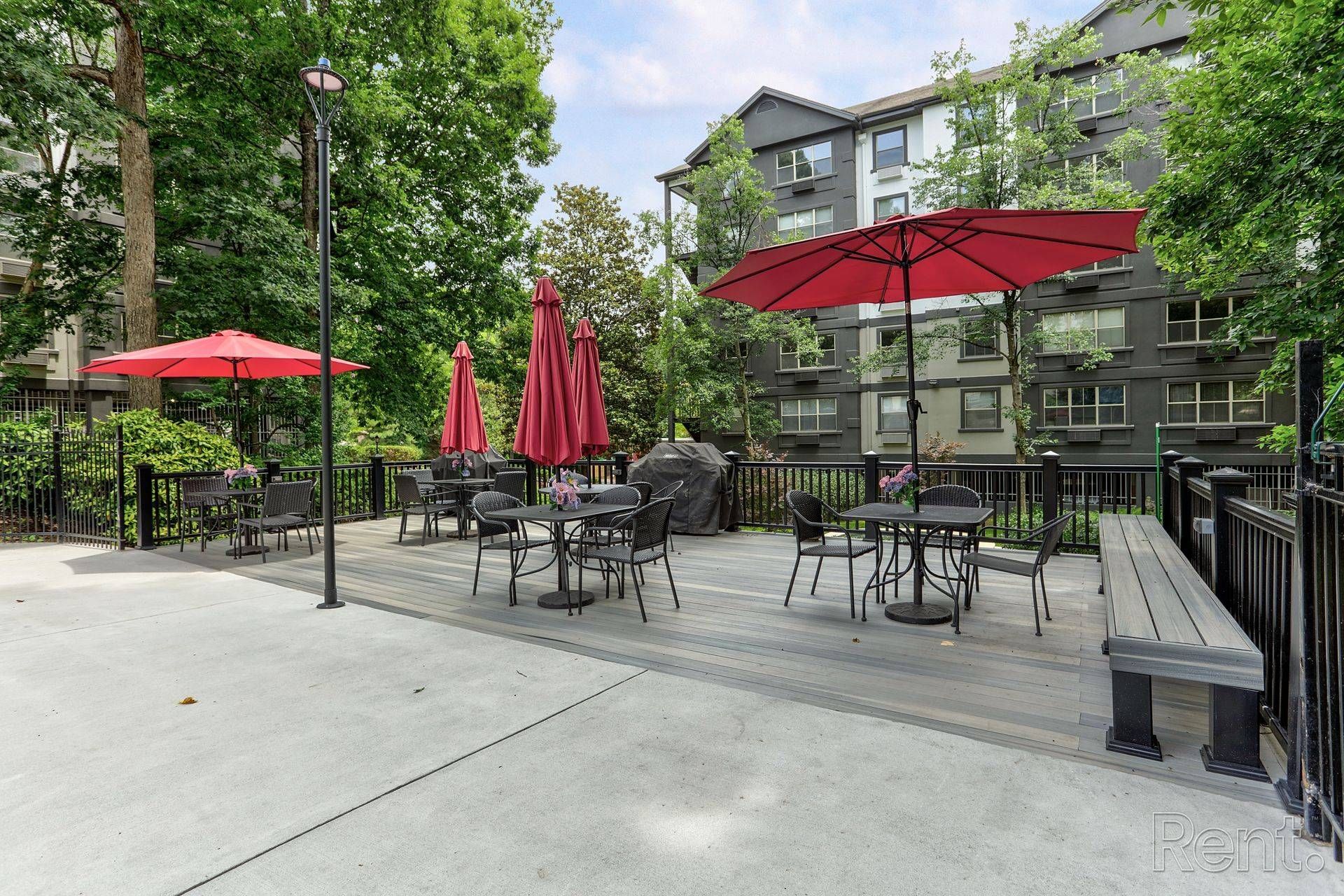 View of an outdoor lounge area at Clairmont Crest senior apartment community surrounded by tall trees.