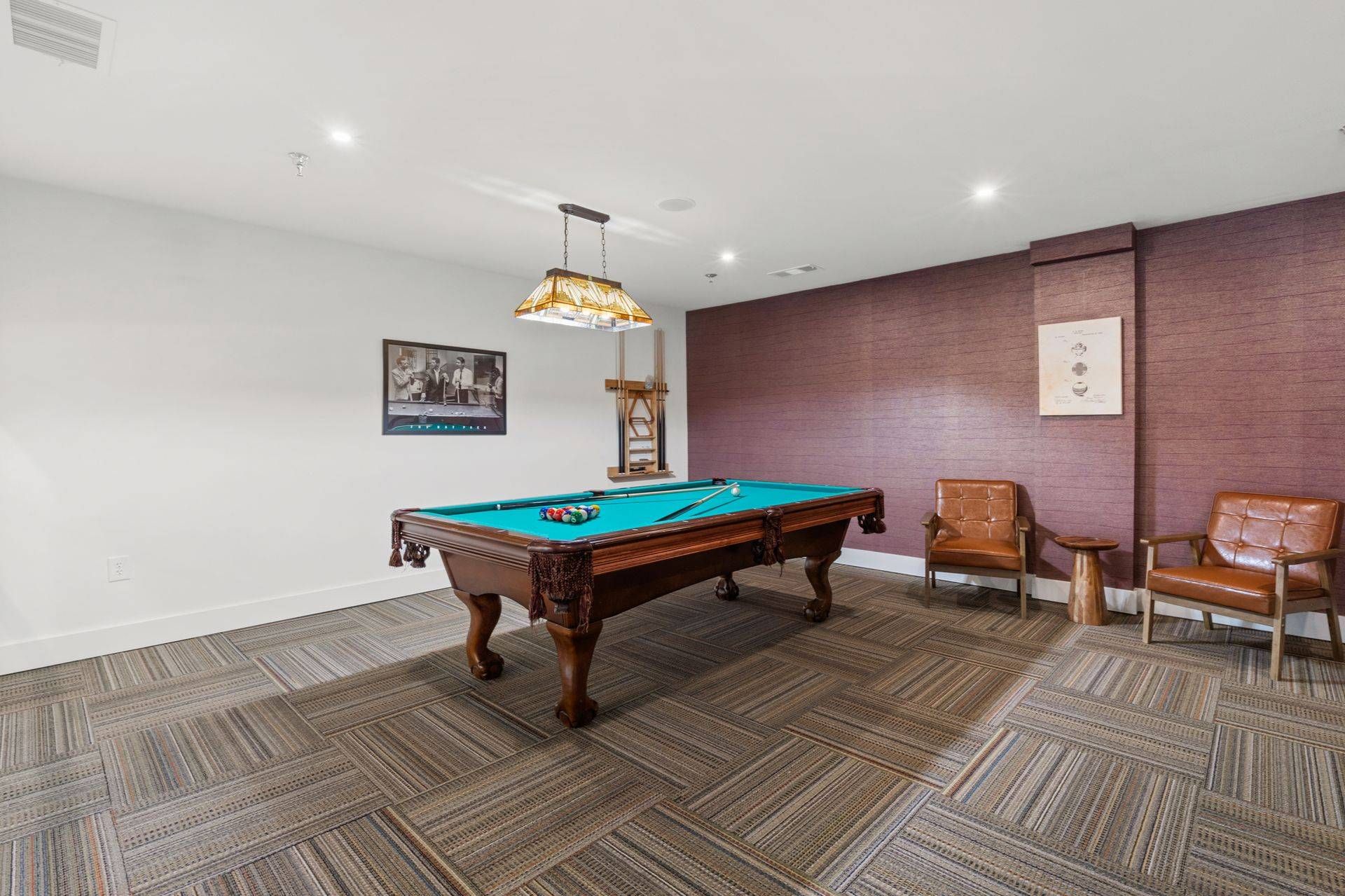 Billiards table with seating nearby in the game room at Clairmont Crest senior living apartments in Decatur, GA.