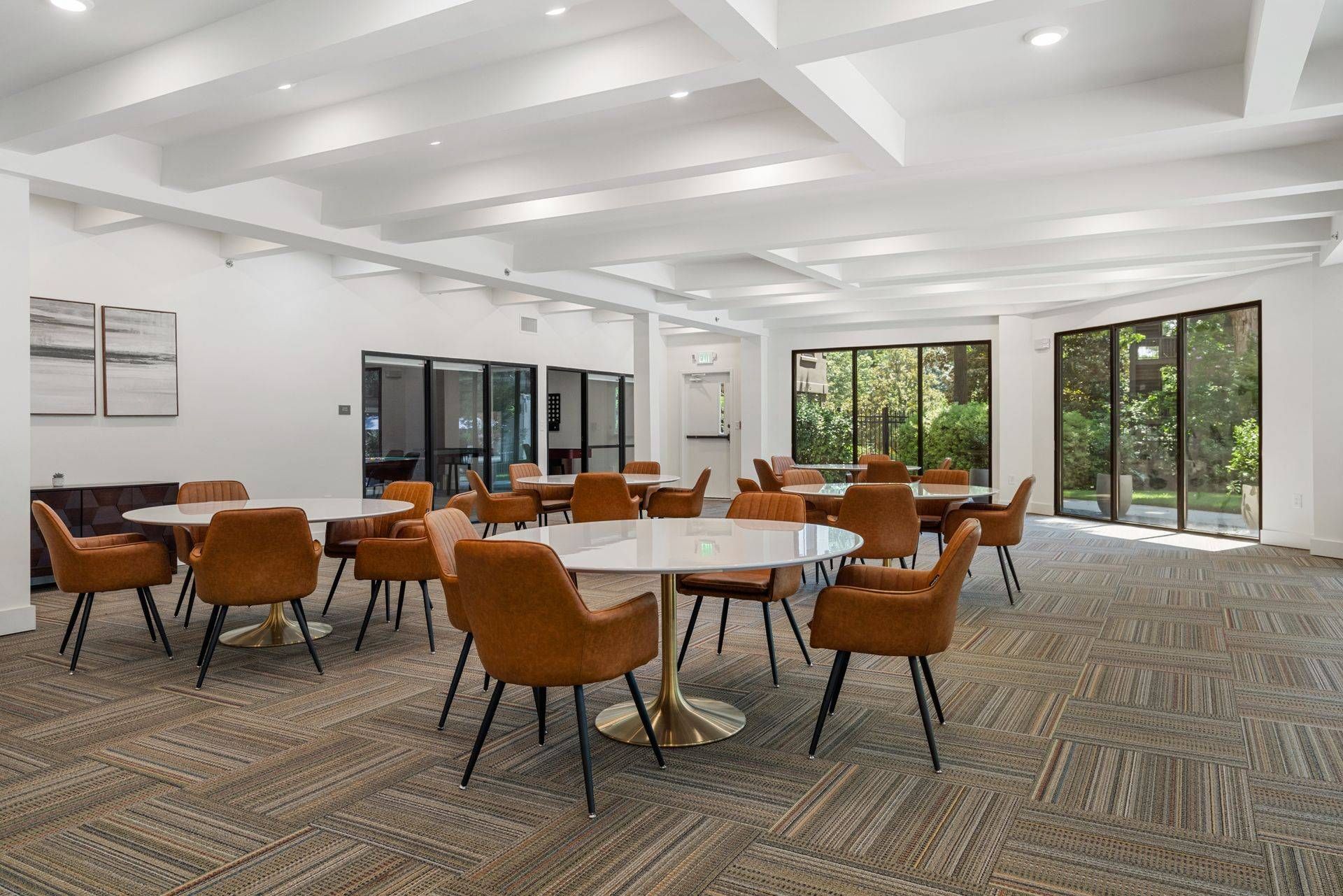 Floor-to-ceiling windows with a view of the trees outside in the dining room at Clairmont Crest senior living apartments in Decatur, GA.