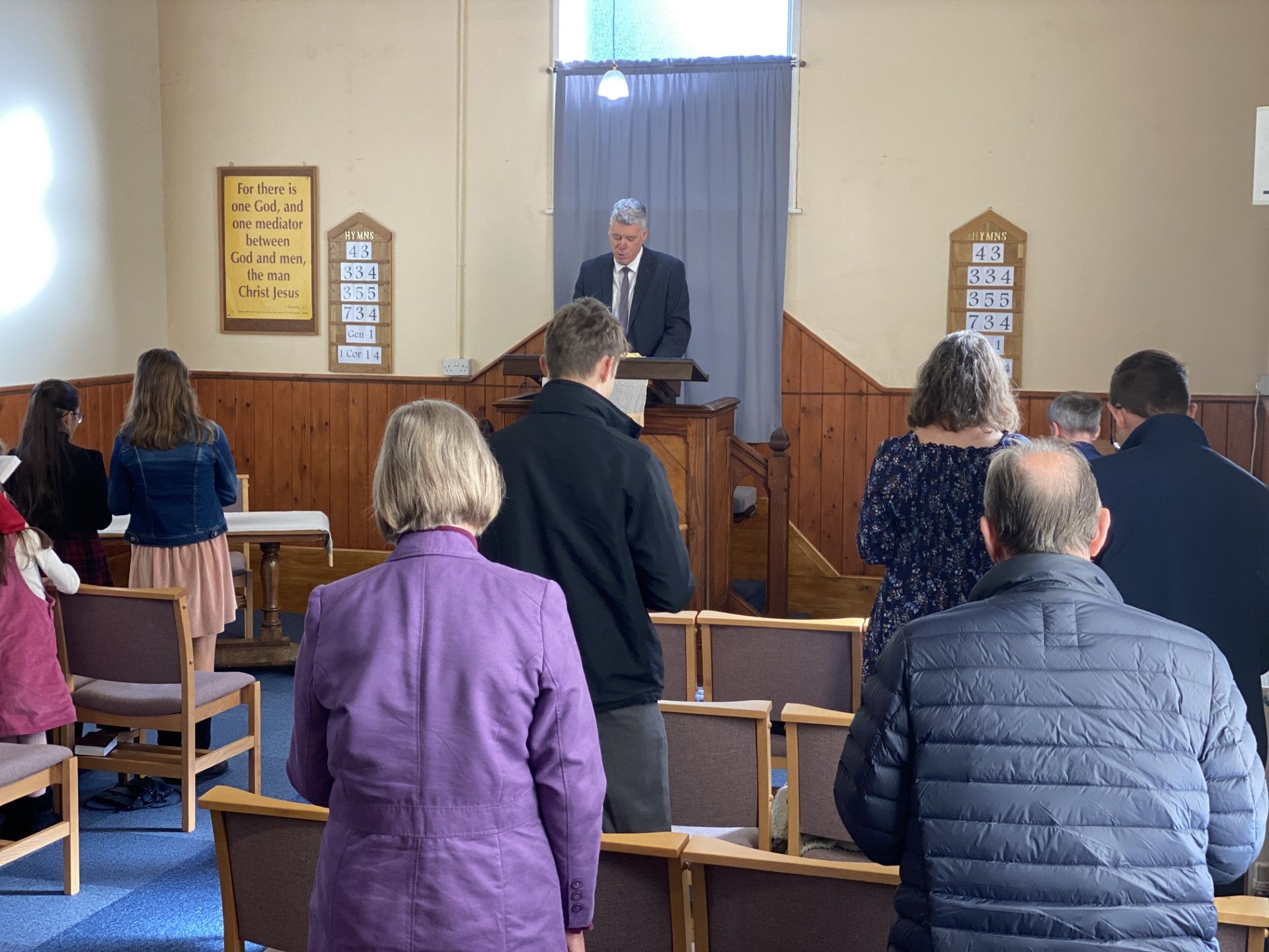 A group of people are sitting in a church while a man stands at a podium.