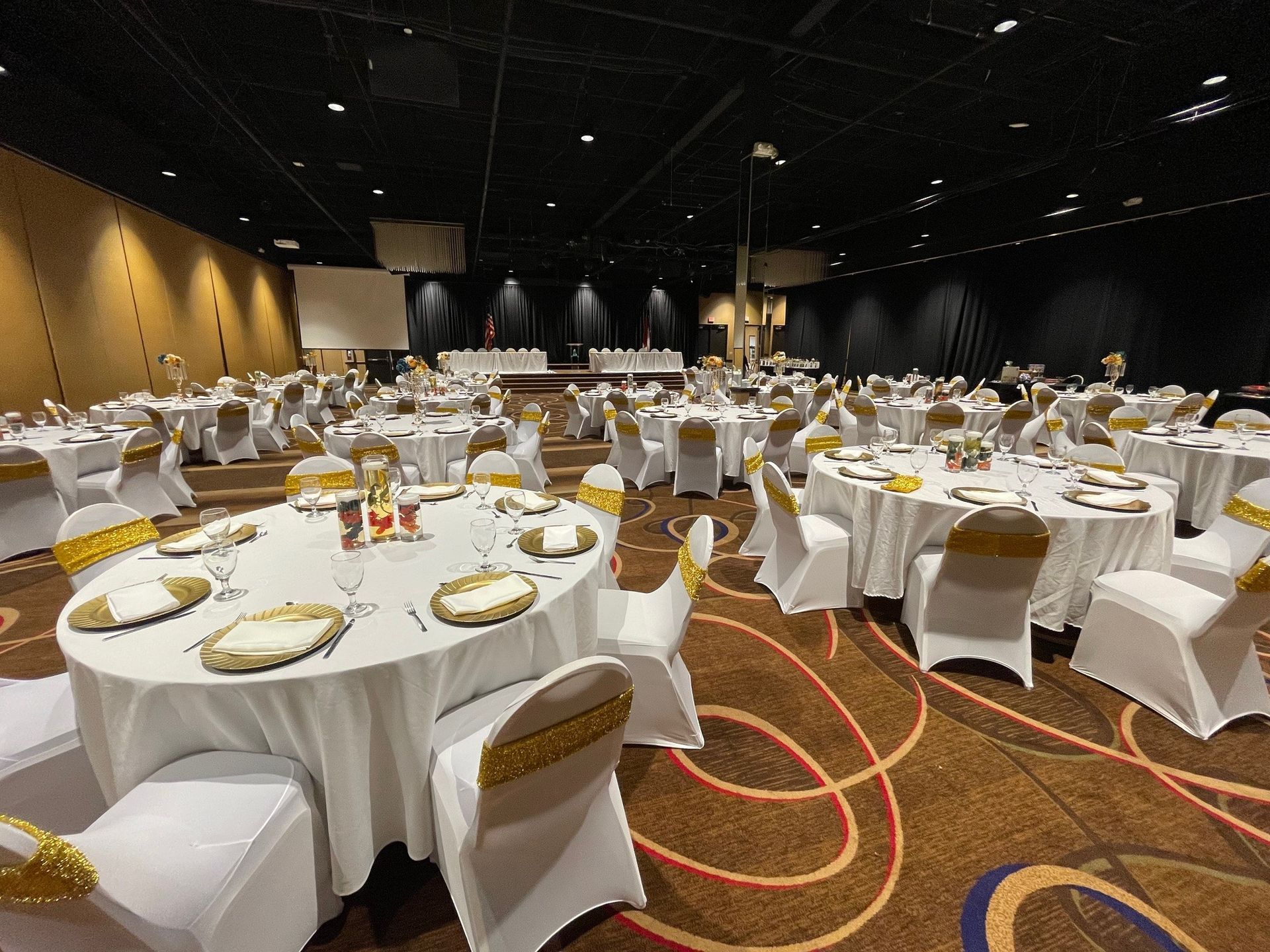 A large room with tables and chairs set up for a wedding reception