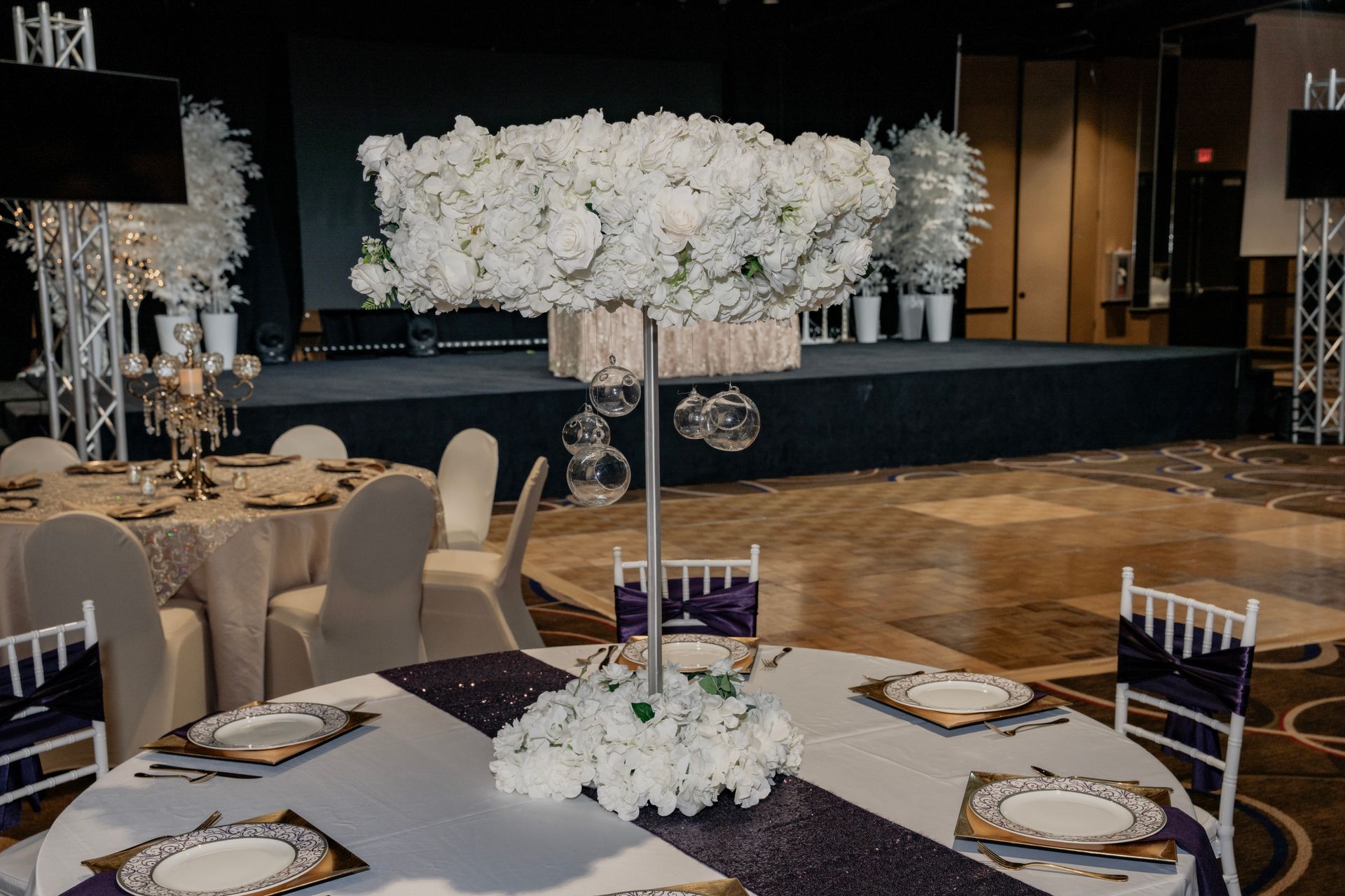 A table set for a wedding reception with a large centerpiece of white flowers.