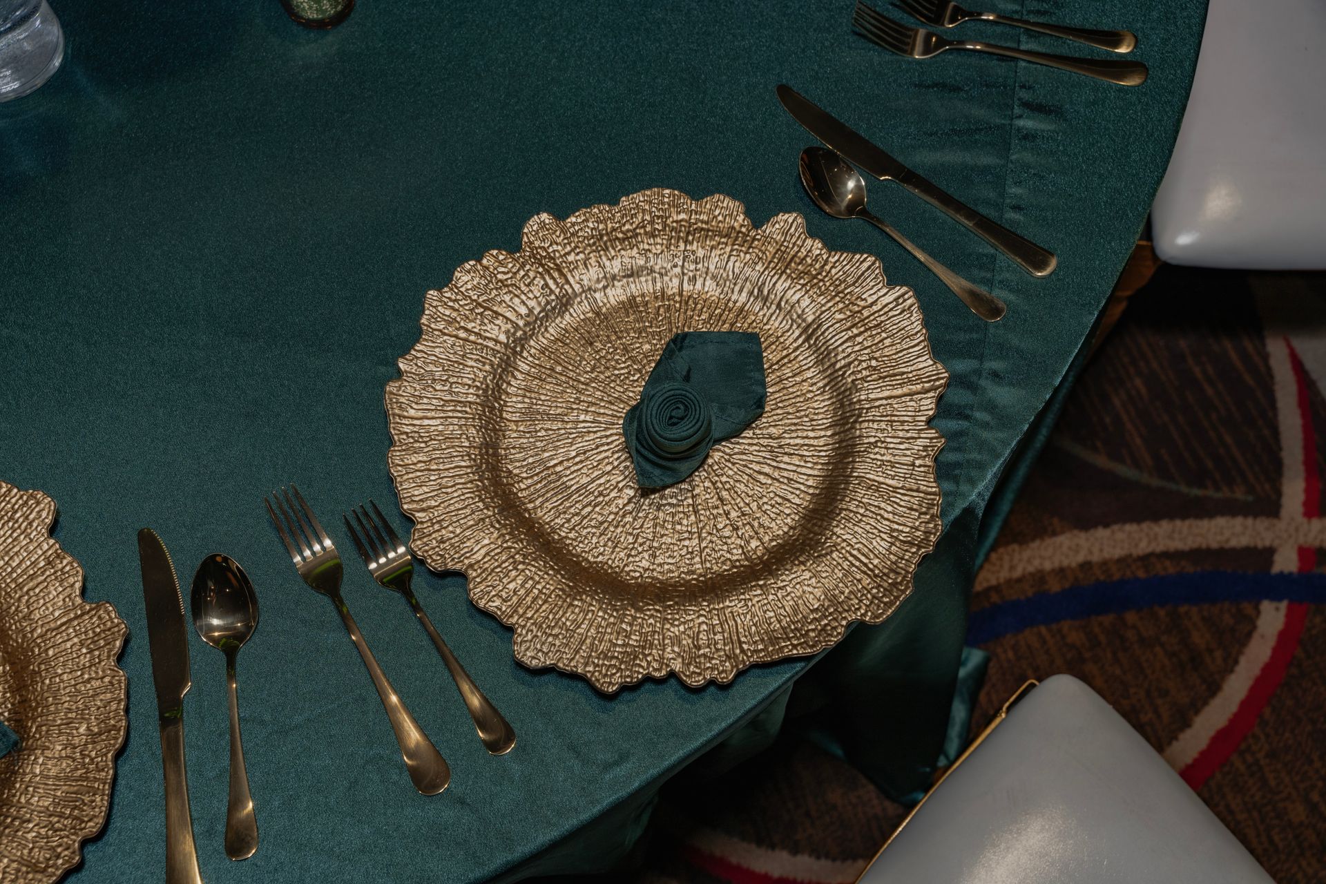 A gold plate with a napkin on it is on a table with silverware.
