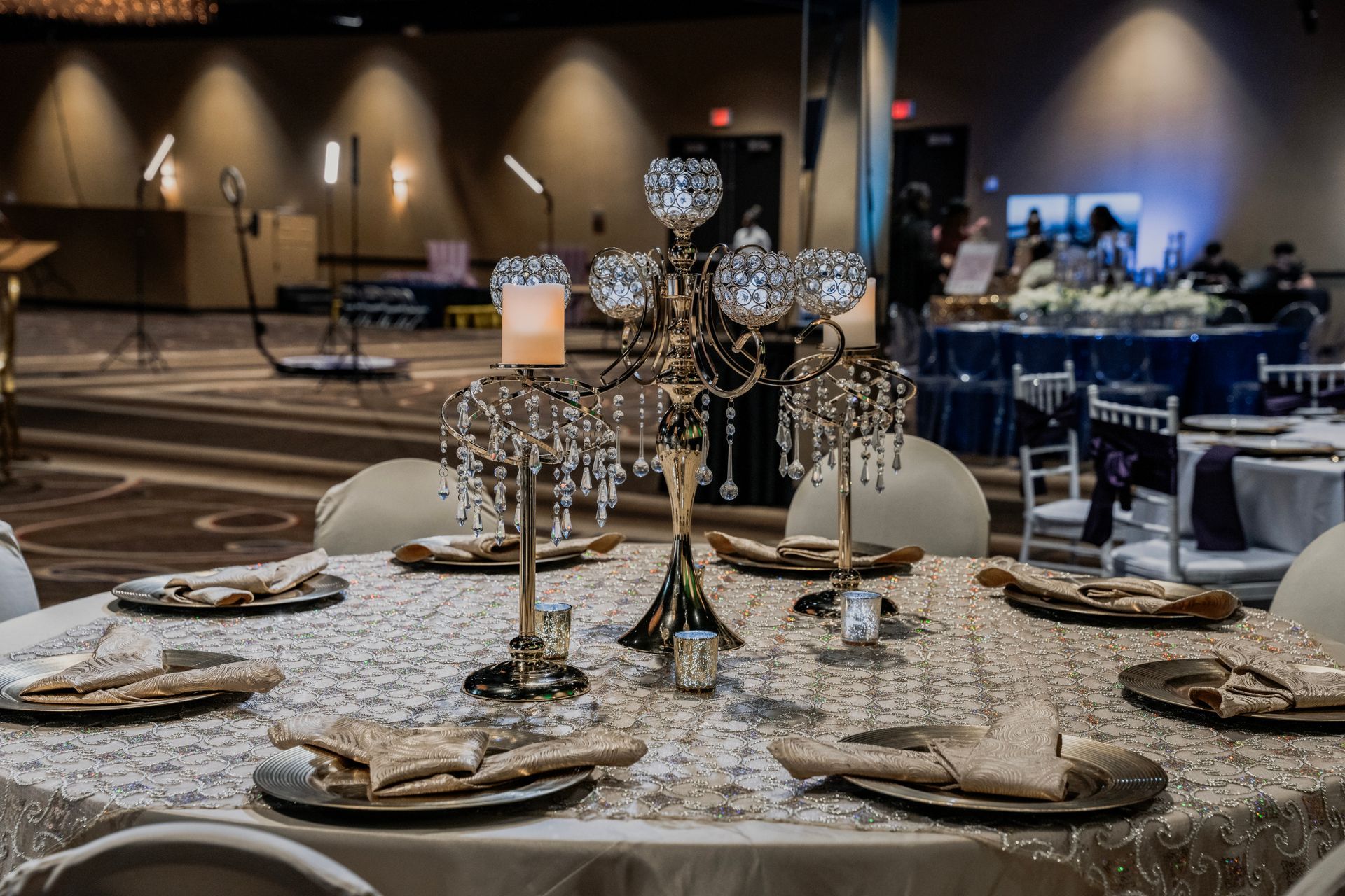 A table set for a wedding reception with plates and candles on it.