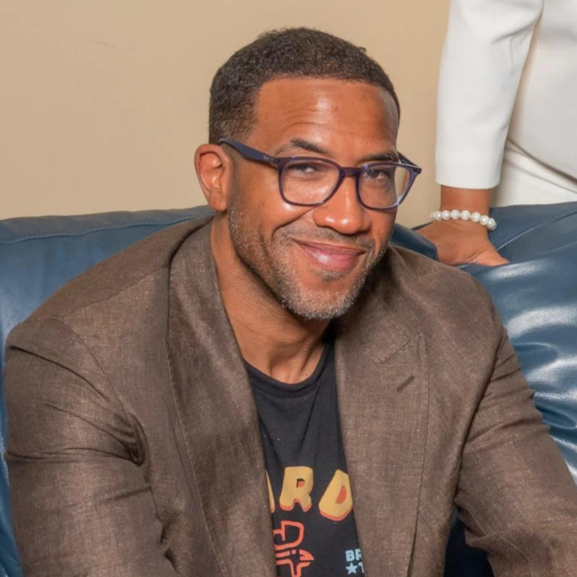 A man wearing glasses is sitting on a couch