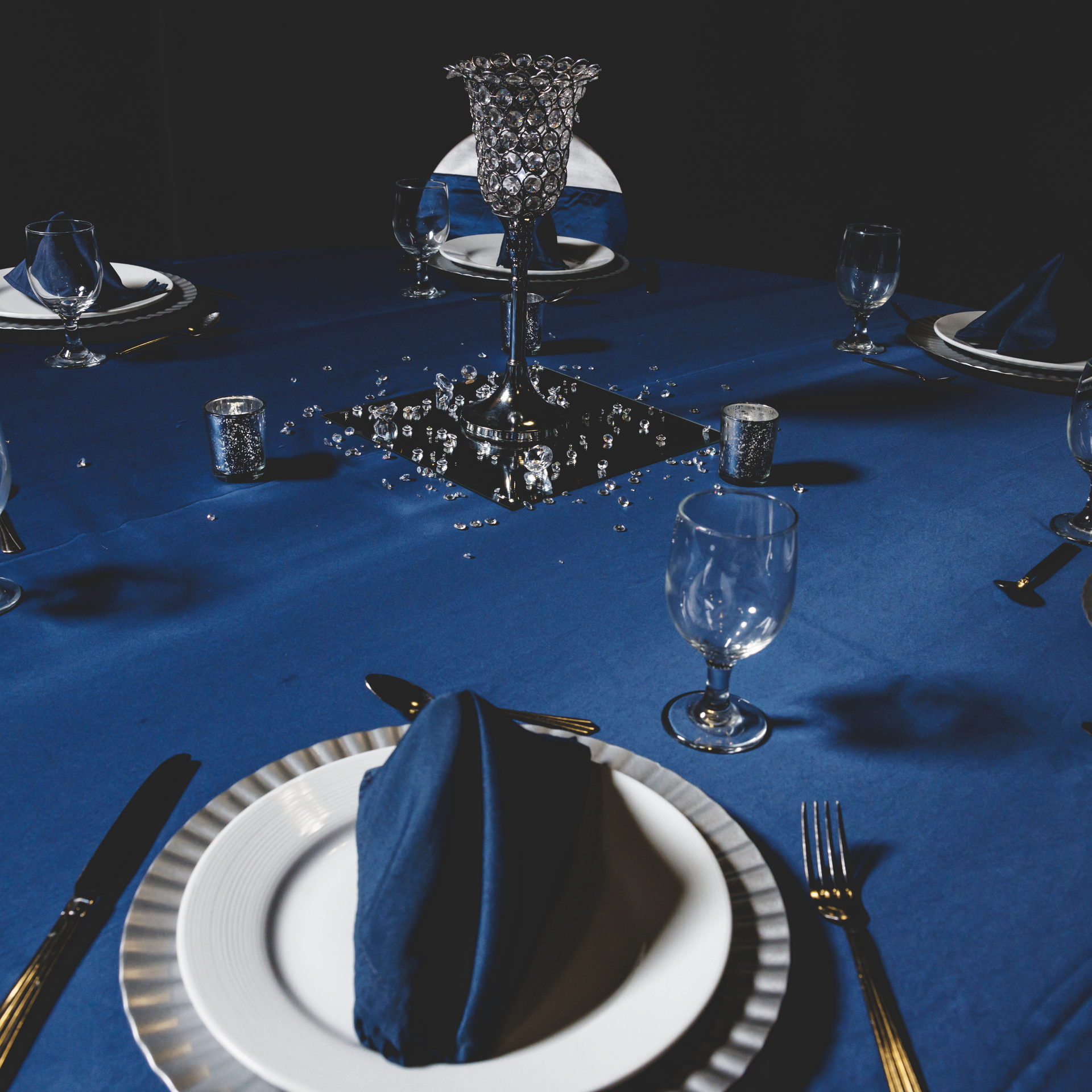 A blue table cloth with plates and silverware on it