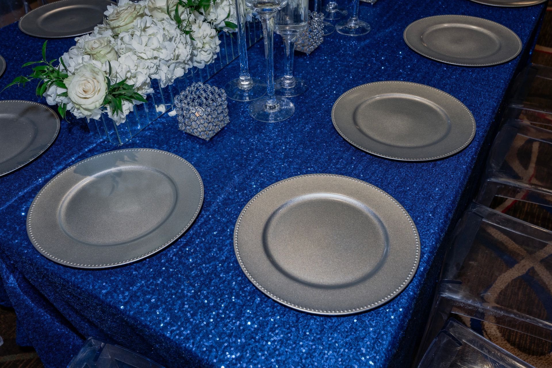 A table with plates and glasses on it and a blue table cloth.