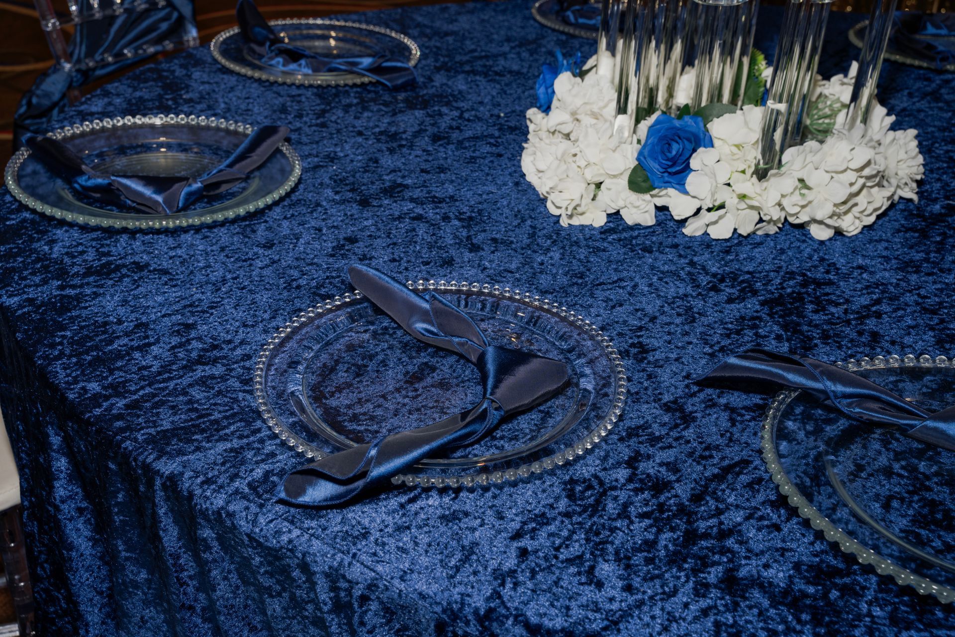 A table with plates , silverware , and a vase of flowers on it.