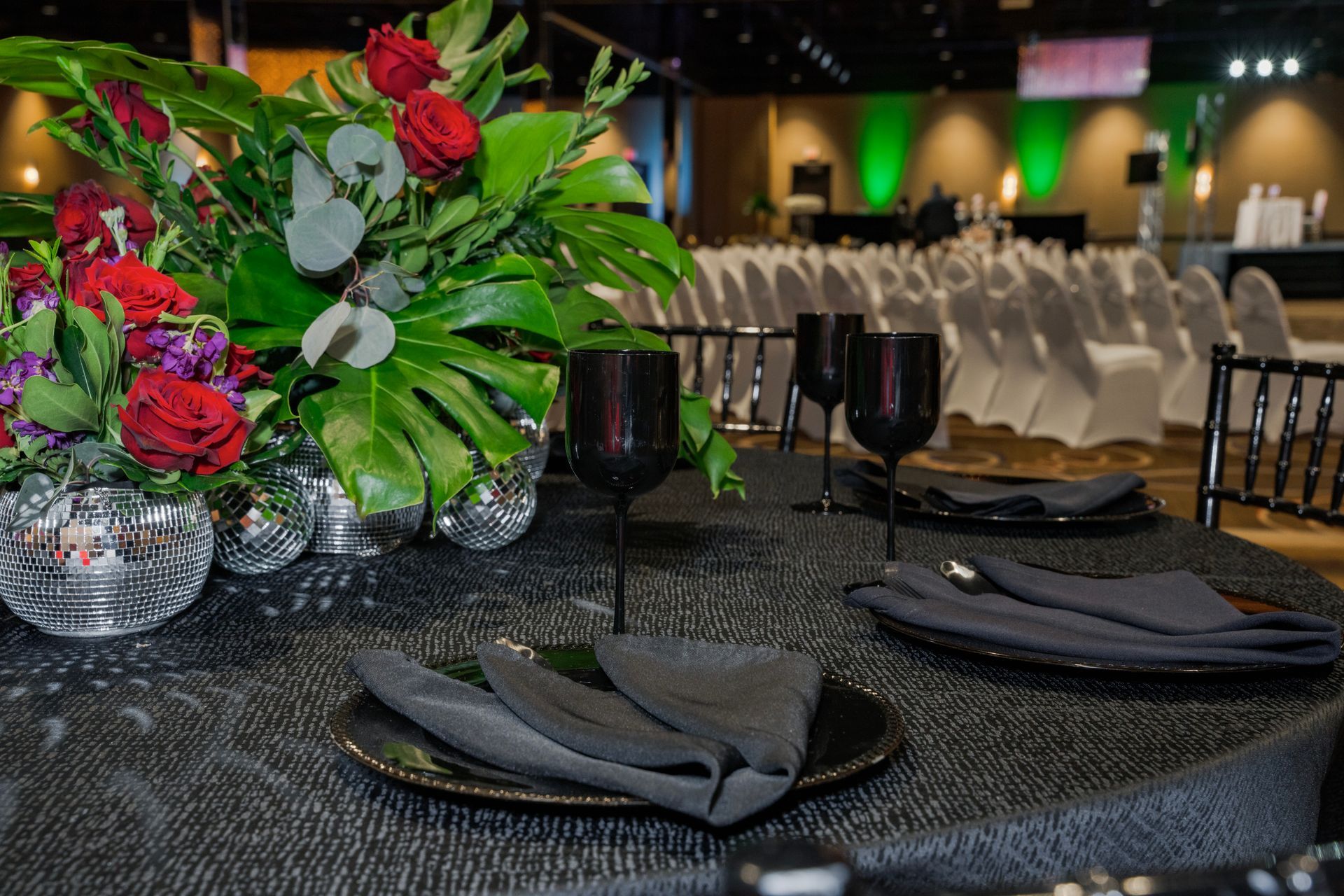A table set for a party with plates , napkins , glasses and a vase of flowers.