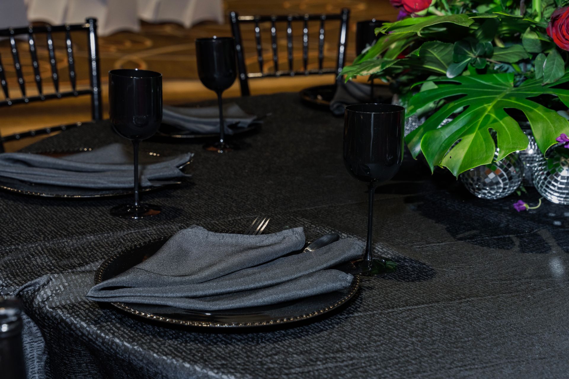 A table with plates , glasses , napkins and a vase of flowers on it.