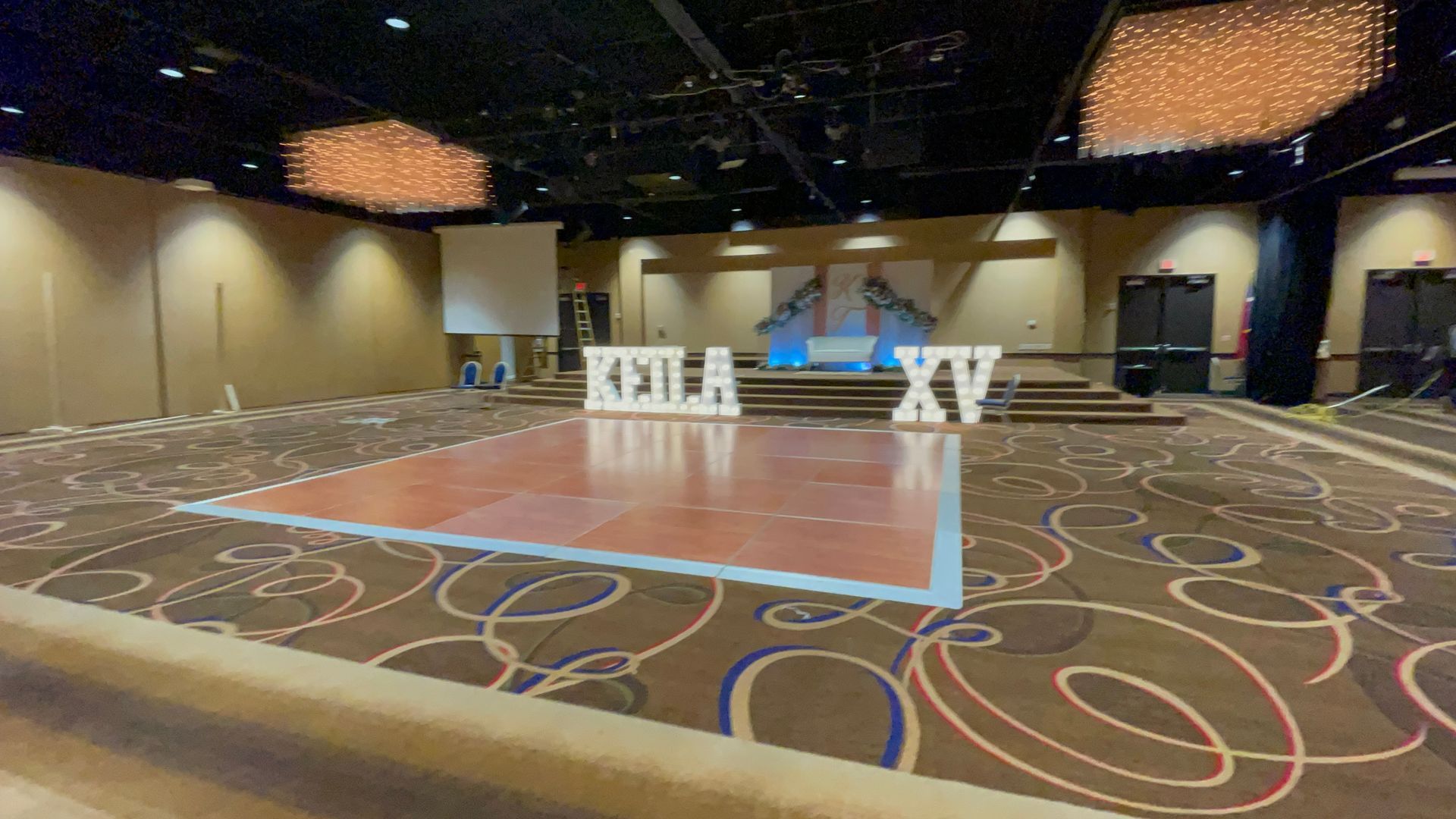 A large empty room with a dance floor and a sign that says 