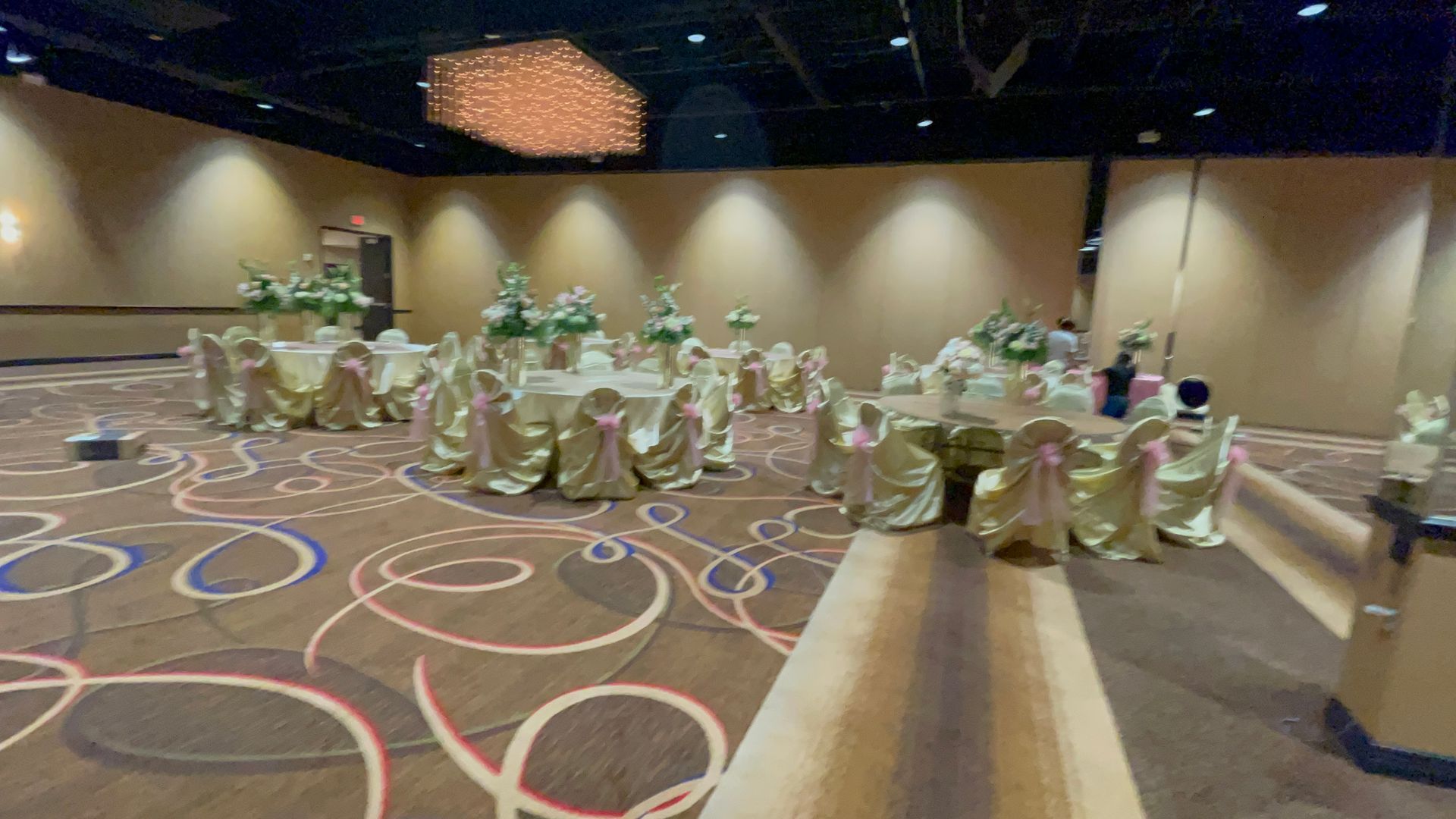 A large room with tables and chairs set up for a quinceañera.