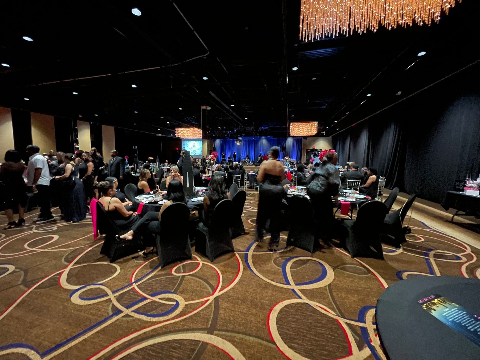 A large room filled with people sitting at tables and chairs.