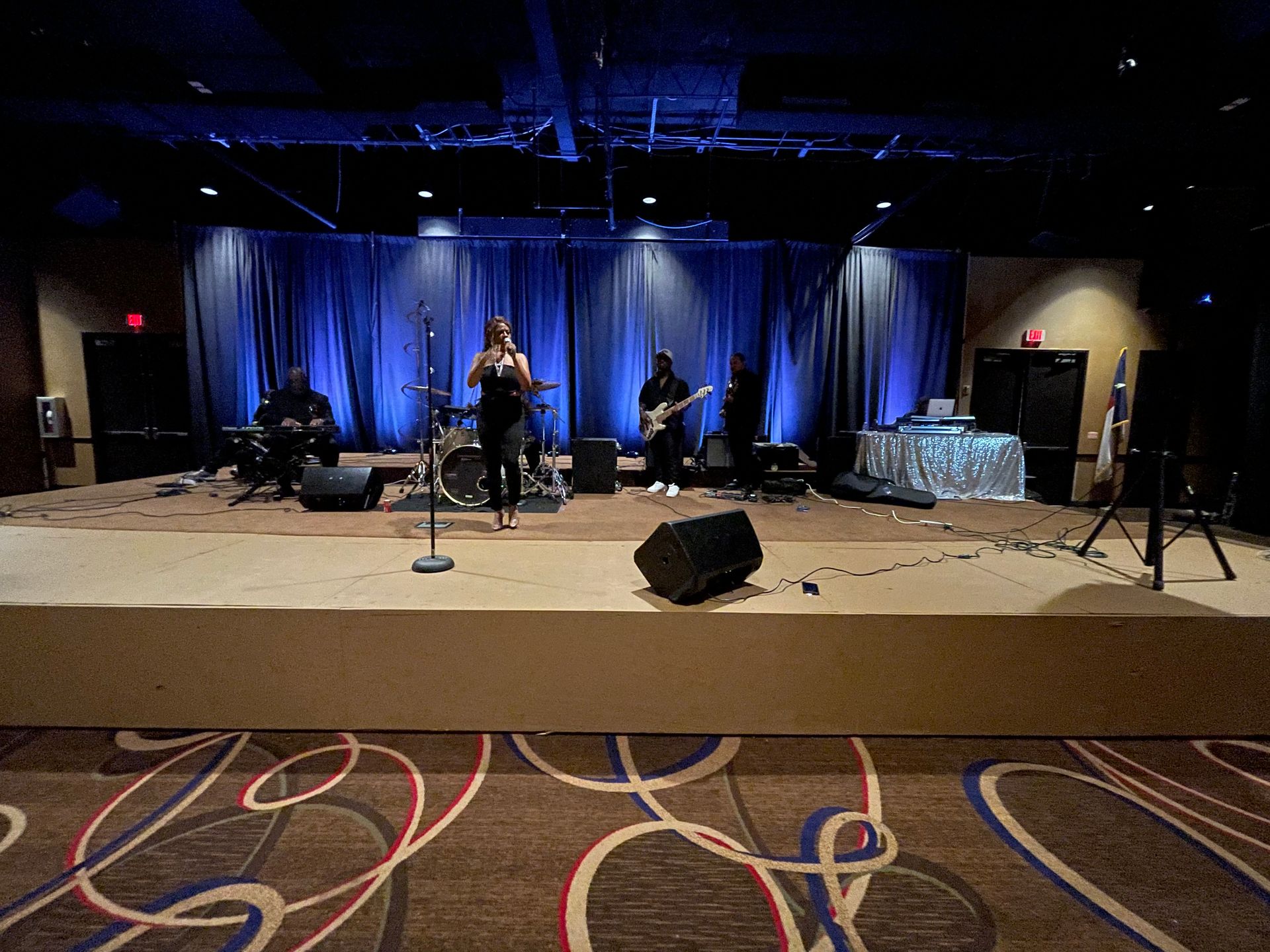 A woman is singing into a microphone on a stage in front of a band.