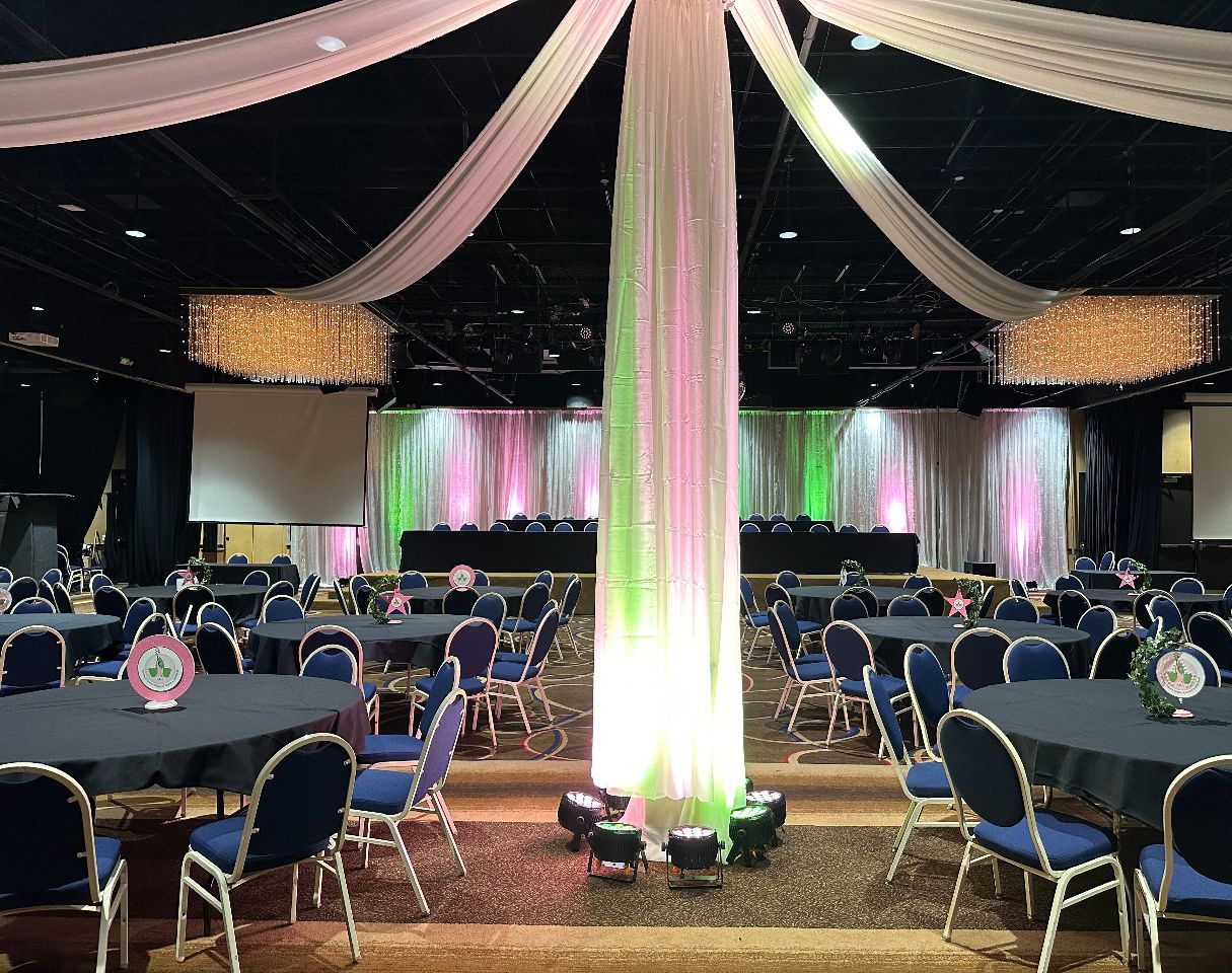 A large room with tables and chairs and a pillar in the middle.