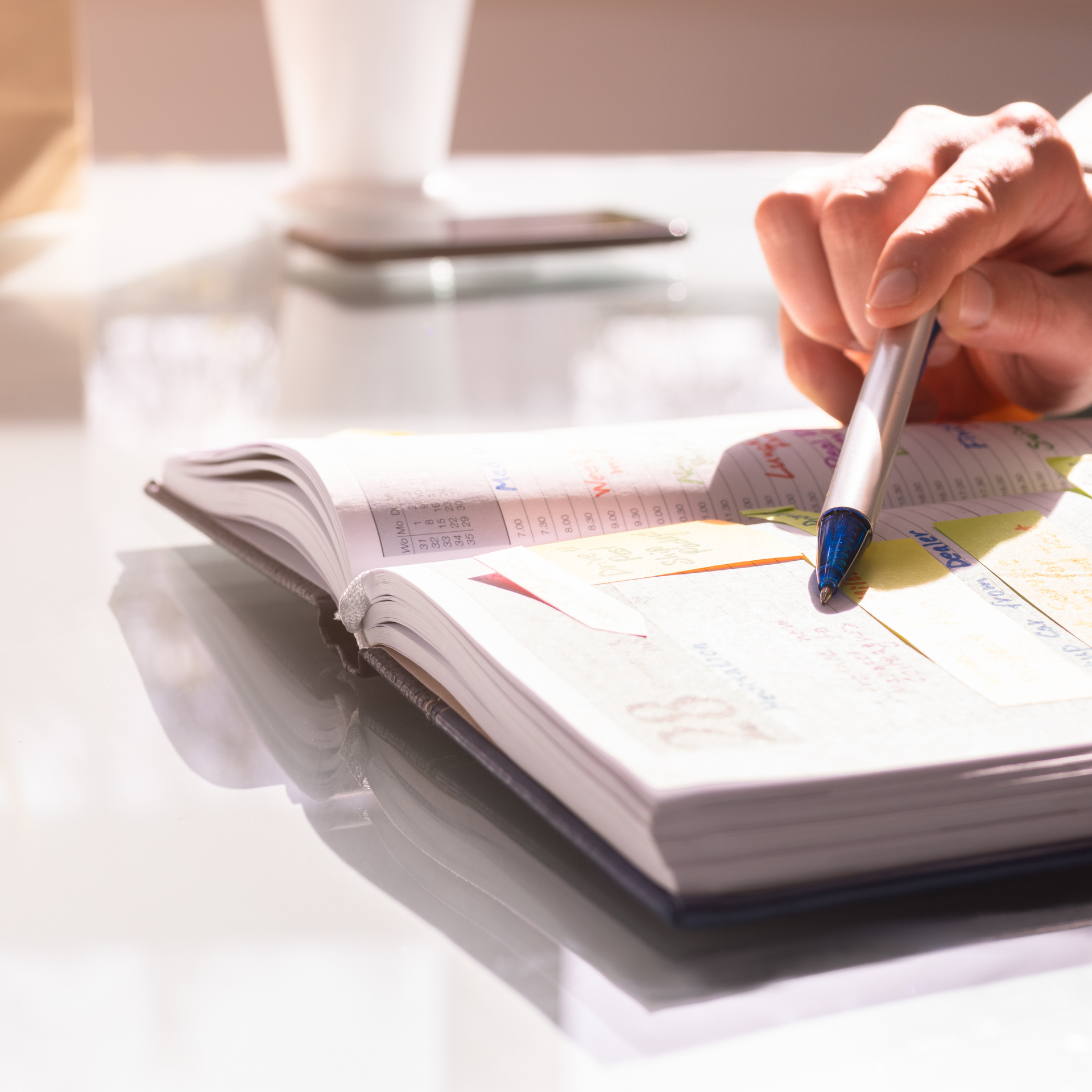 A person is writing in a notebook with a pen